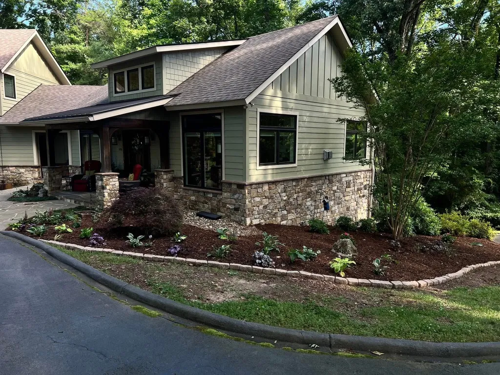 Maintained planting beds with fresh mulch, shrubs, and defined edging beside a home